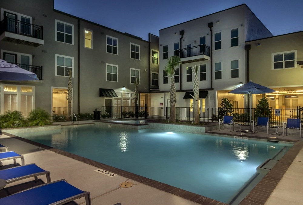 a swimming pool at night in front of an apartment building