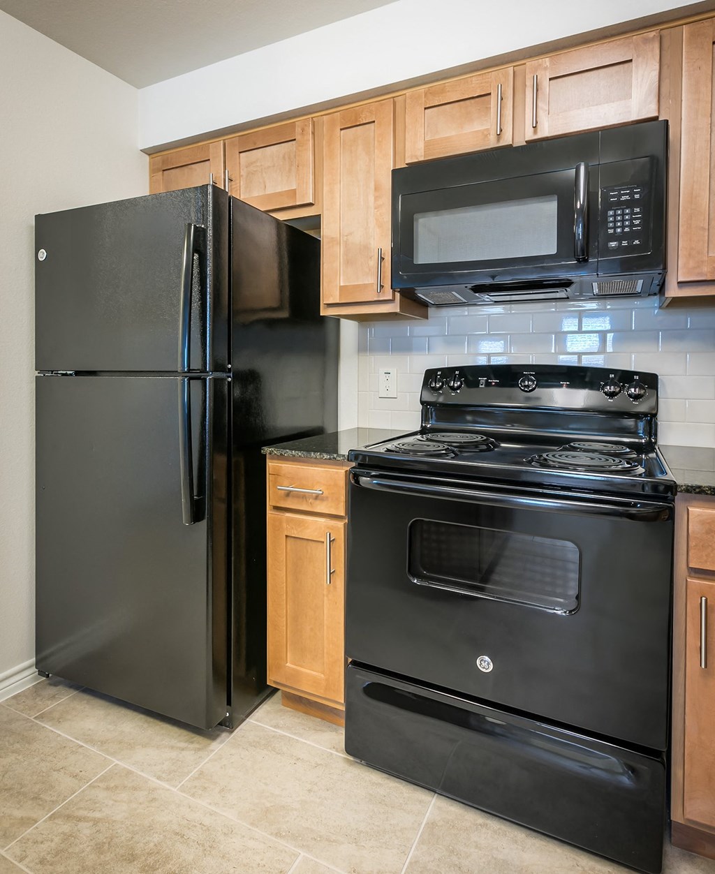 an updated kitchen with black appliances and wood cabinets