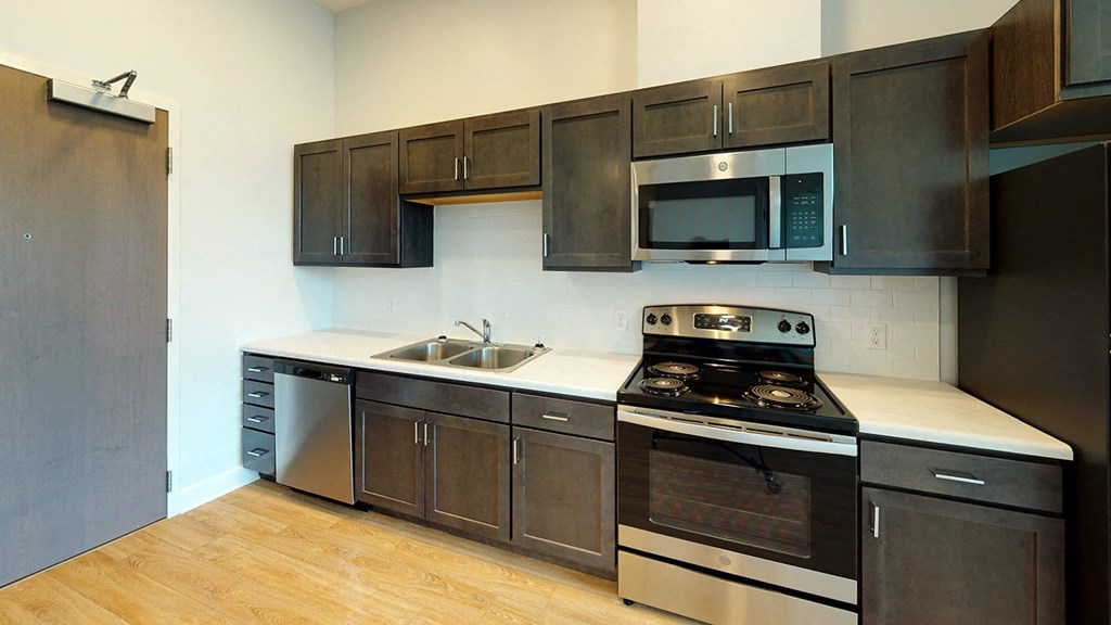 a kitchen with stainless steel appliances and wooden cabinets at City Square 162