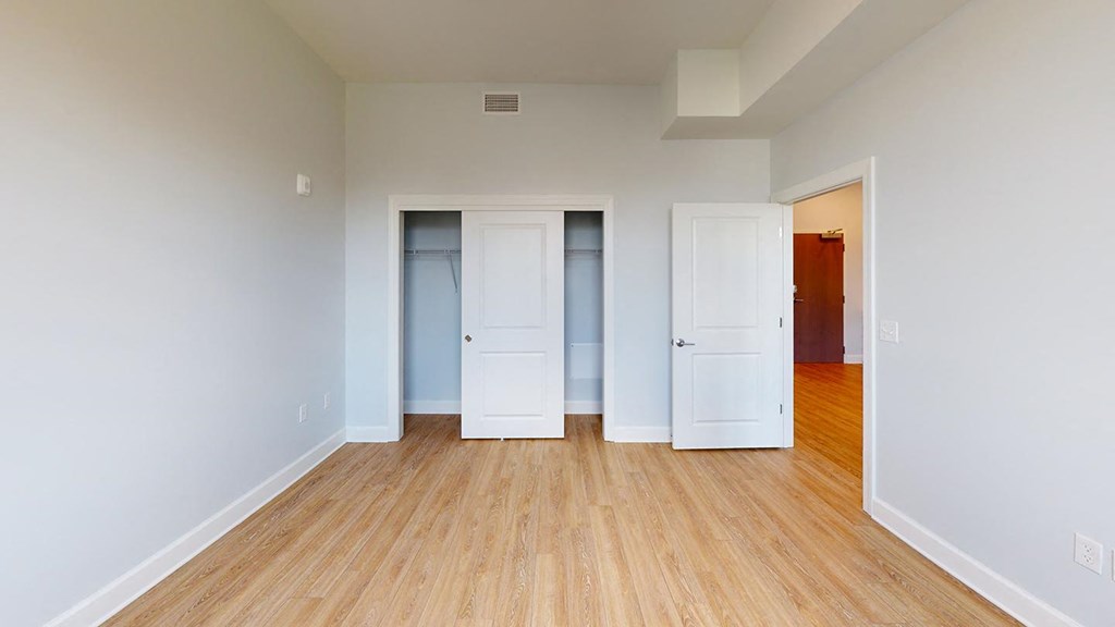 an empty room with three closets and a wood floor at City Square 162