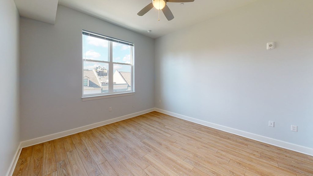 an empty bedroom with a window and wood floors at City Square 162