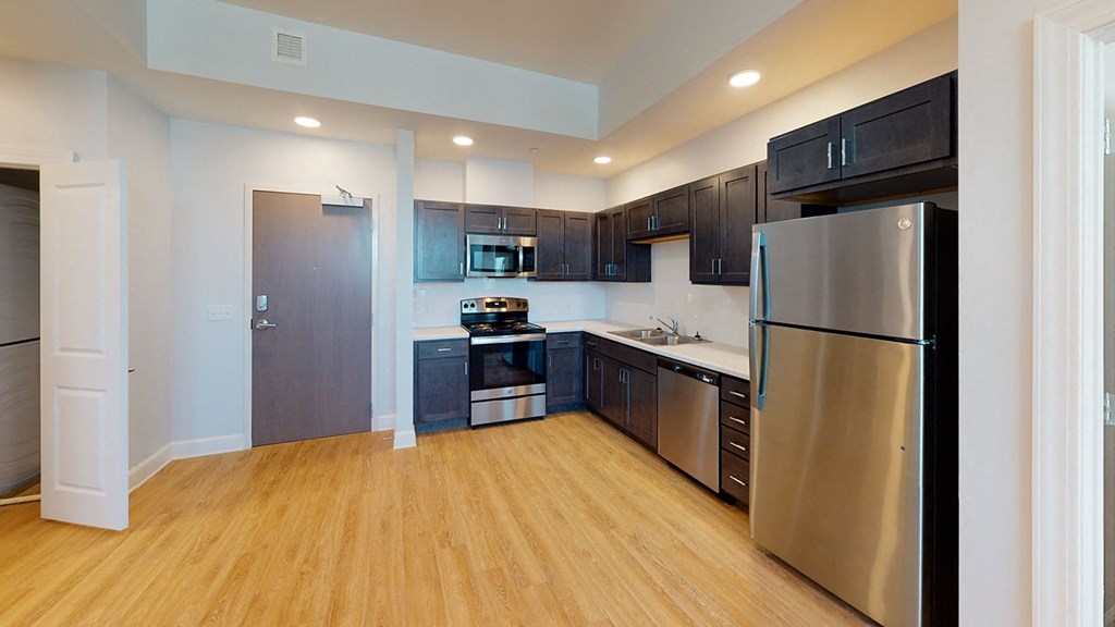 a large kitchen with stainless steel appliances and black cabinets at City Square 162
