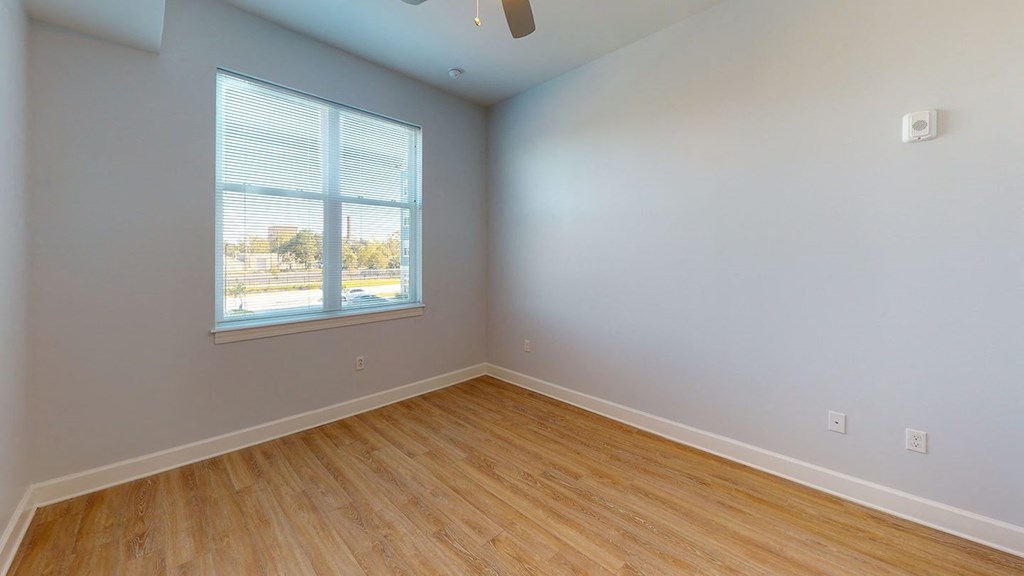 an empty bedroom with wood floors and a window at City Square 162