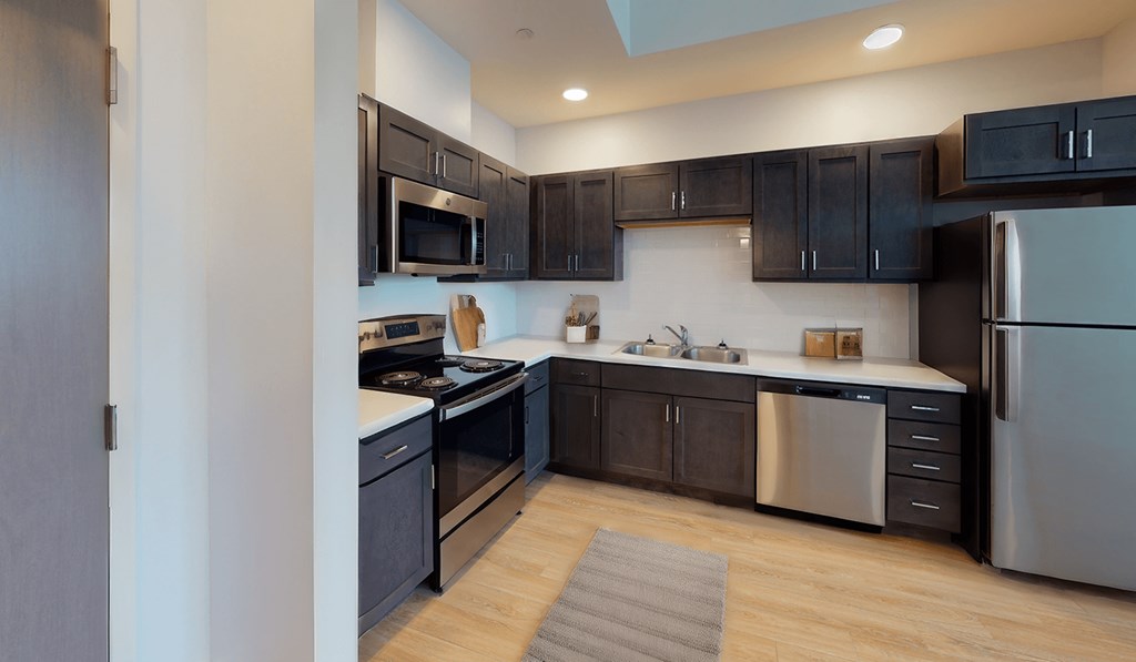 an empty kitchen with black cabinets and stainless steel appliances at City Square 162