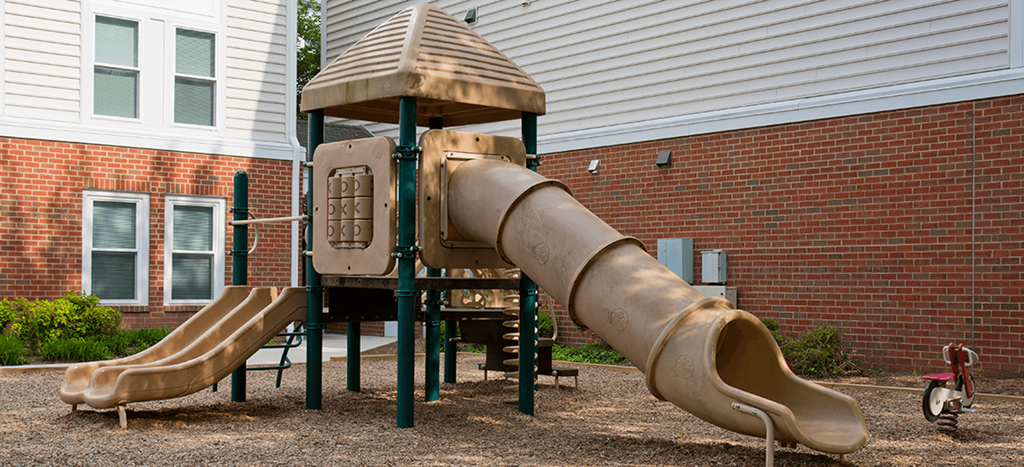 Playground a playground with a slide and a playset in front of a brick building