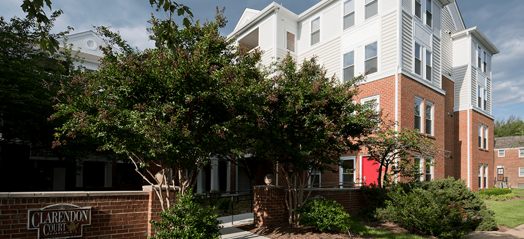 Clarendon Court Apartments building with a courtyard with bushes and trees