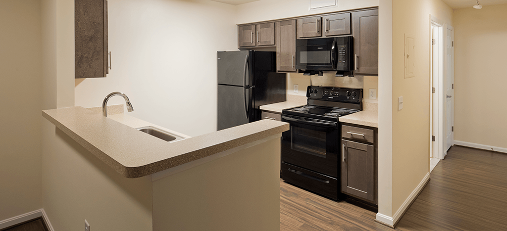 a model kitchen with black appliances and brown cabinets