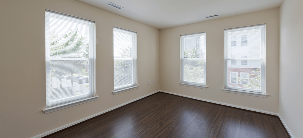 an empty bedroom with wood floors and three windows