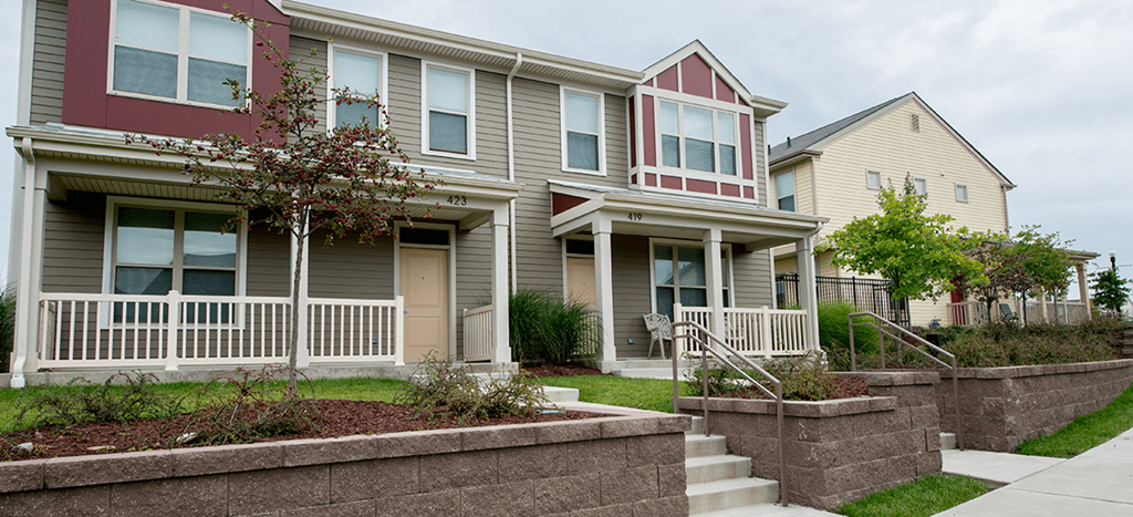 a row of apartment homes with stairs and a sidewalk in front of them