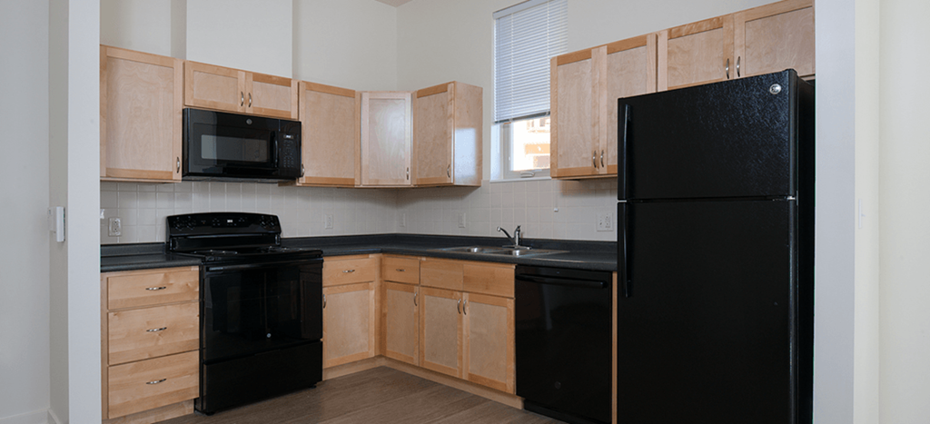 an empty kitchen with black appliances and wooden cabinets