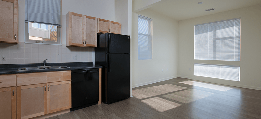 an empty kitchen with a black refrigerator and wooden cabinets