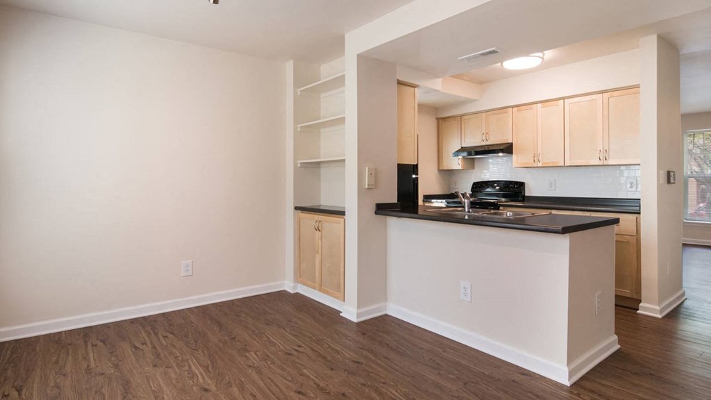 a kitchen with a counter top and black appliances and wood cabinets at Crawford Square Apartments & Townhomes