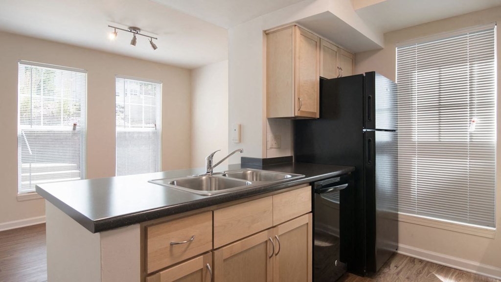 a kitchen with a sink and a refrigerator at Crawford Square Apartments & Townhomes