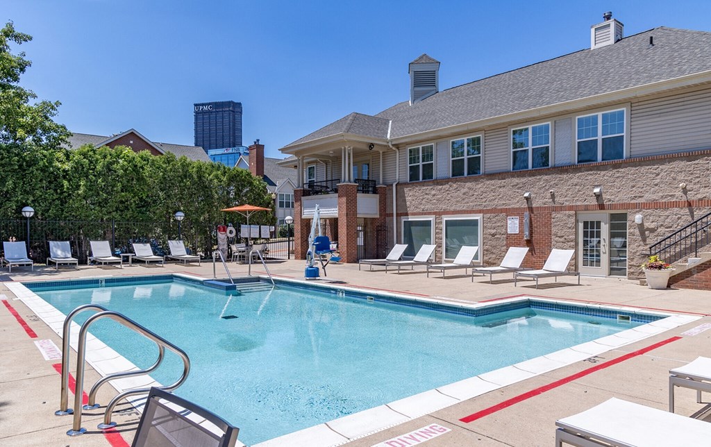 a swimming pool with lounge chairs and a building in the background at Crawford Square Apartments & Townhomes
