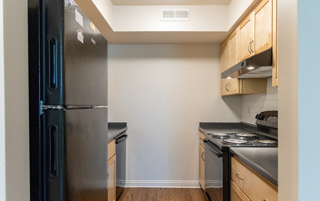a renovated kitchen with stainless steel appliances and wooden cabinets at Crawford Square Apartments & Townhomes
