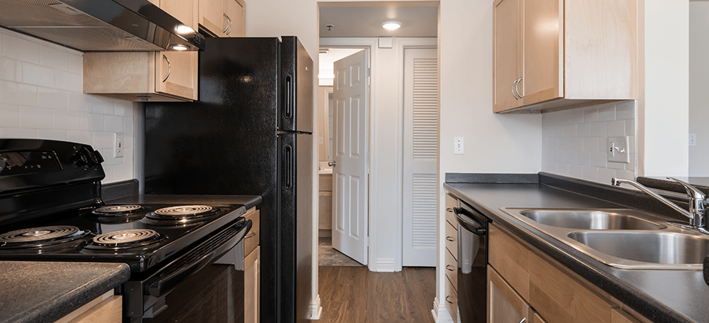 a kitchen with black appliances and a door to a hallway