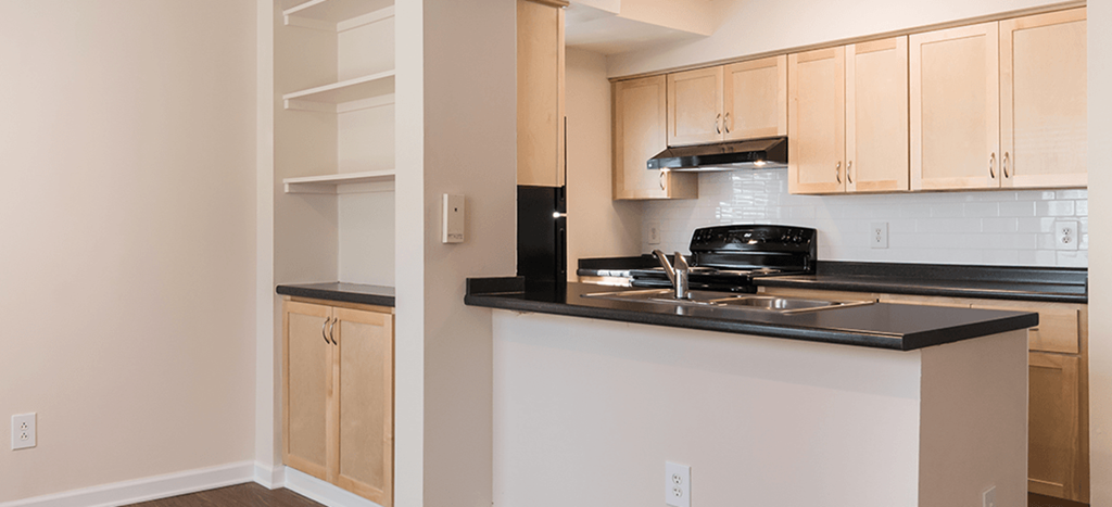 a view of a kitchen with a stove and counter top with additional shelving in a dining area