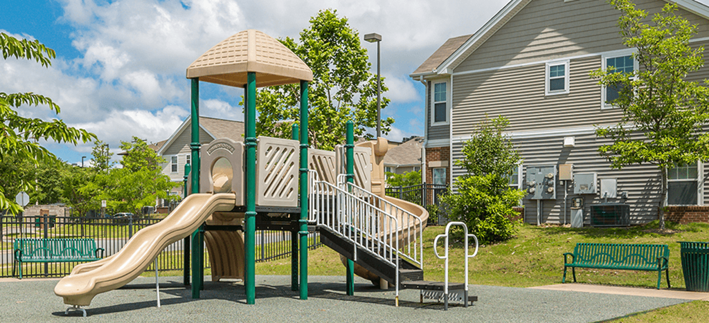 a playground with a slide and a swing set in front of Cumberland Manor Metropolitan Village