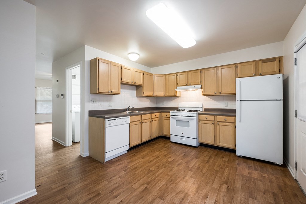 an empty kitchen with white appliances and wood cabinets at Duneland Village apartments and Townhomes in Gary, IN