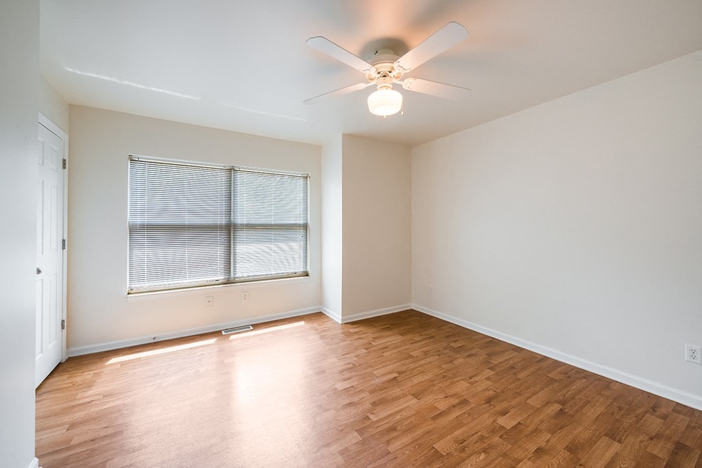 an empty living room with wood floors and a ceiling fan at Duneland Village apartments and Townhomes in Gary, IN