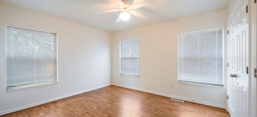an empty living room with wood floors and a ceiling fan