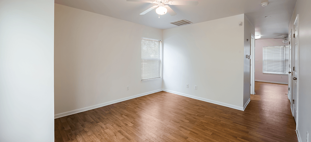 an empty living room with wood floors and white walls
