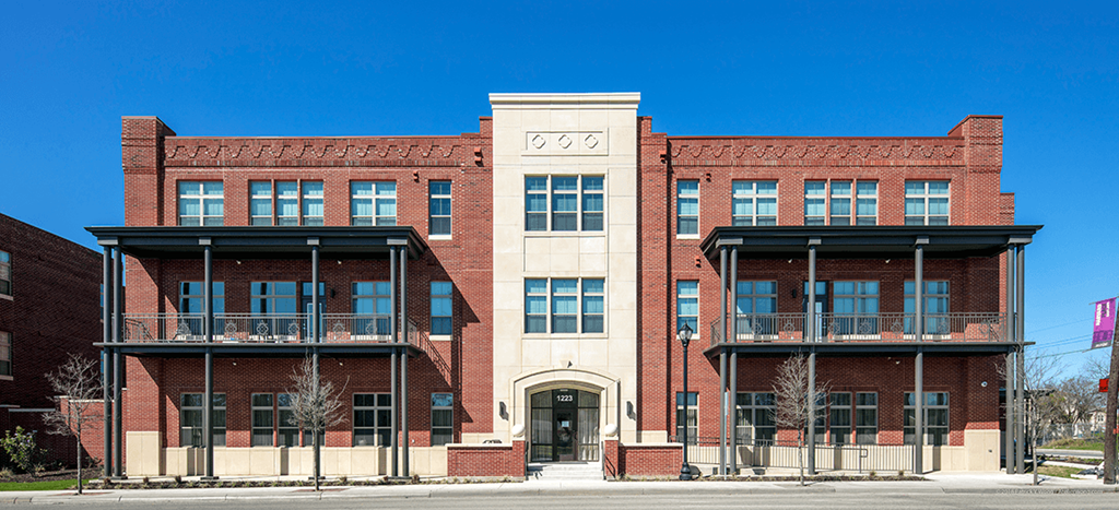 a red brick building on the corner of a street at East Meadows Apartments