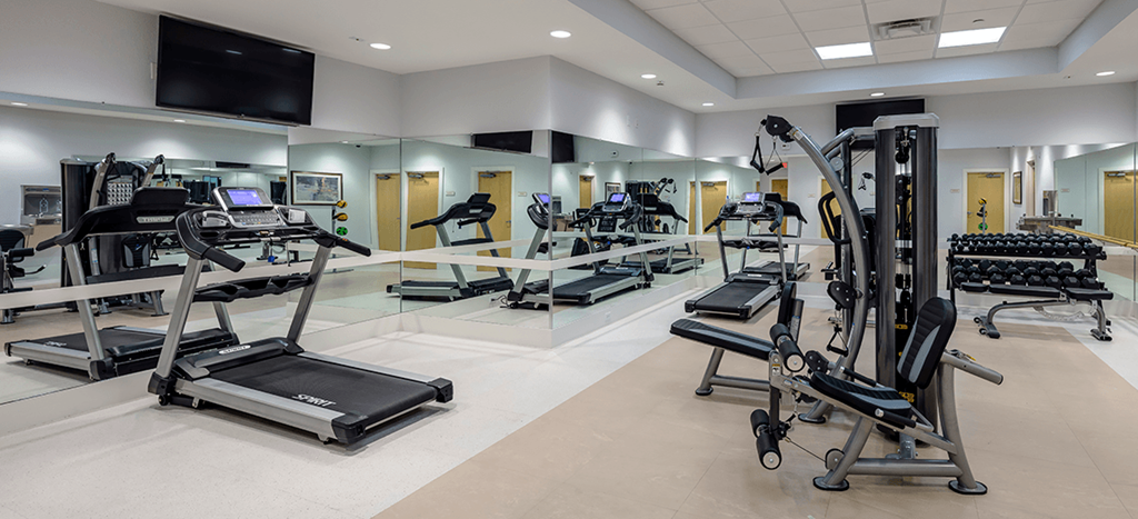 a gym with cardio equipment and weights at East Meadows Apartments