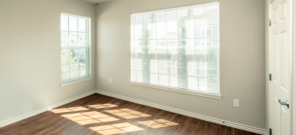 an empty room with a large window and a wooden floor