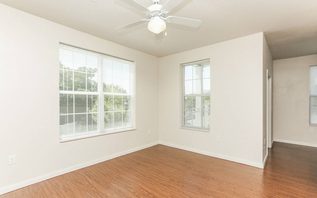 an empty living room with wood floors and a ceiling fan at East Meadows apartments in San Antonio, TX