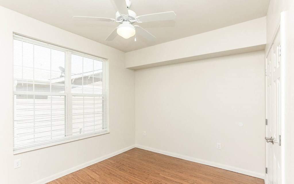 an empty bedroom with a ceiling fan and a window at East Meadows apartments in San Antonio, TX