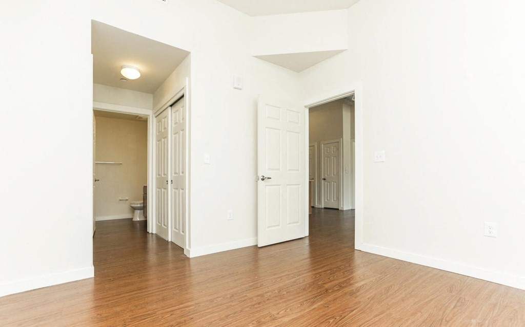 an empty living room with wood flooring and white walls at East Meadows apartments in San Antonio, TX