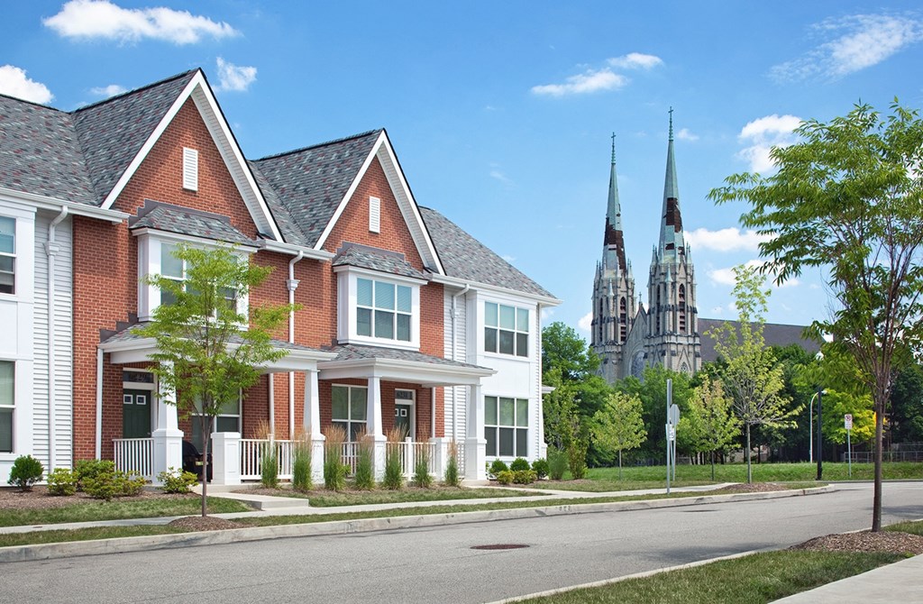 a row of houses on a street with a church in the background