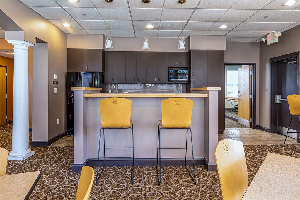 A kitchen area with a bar and two yellow chairs.