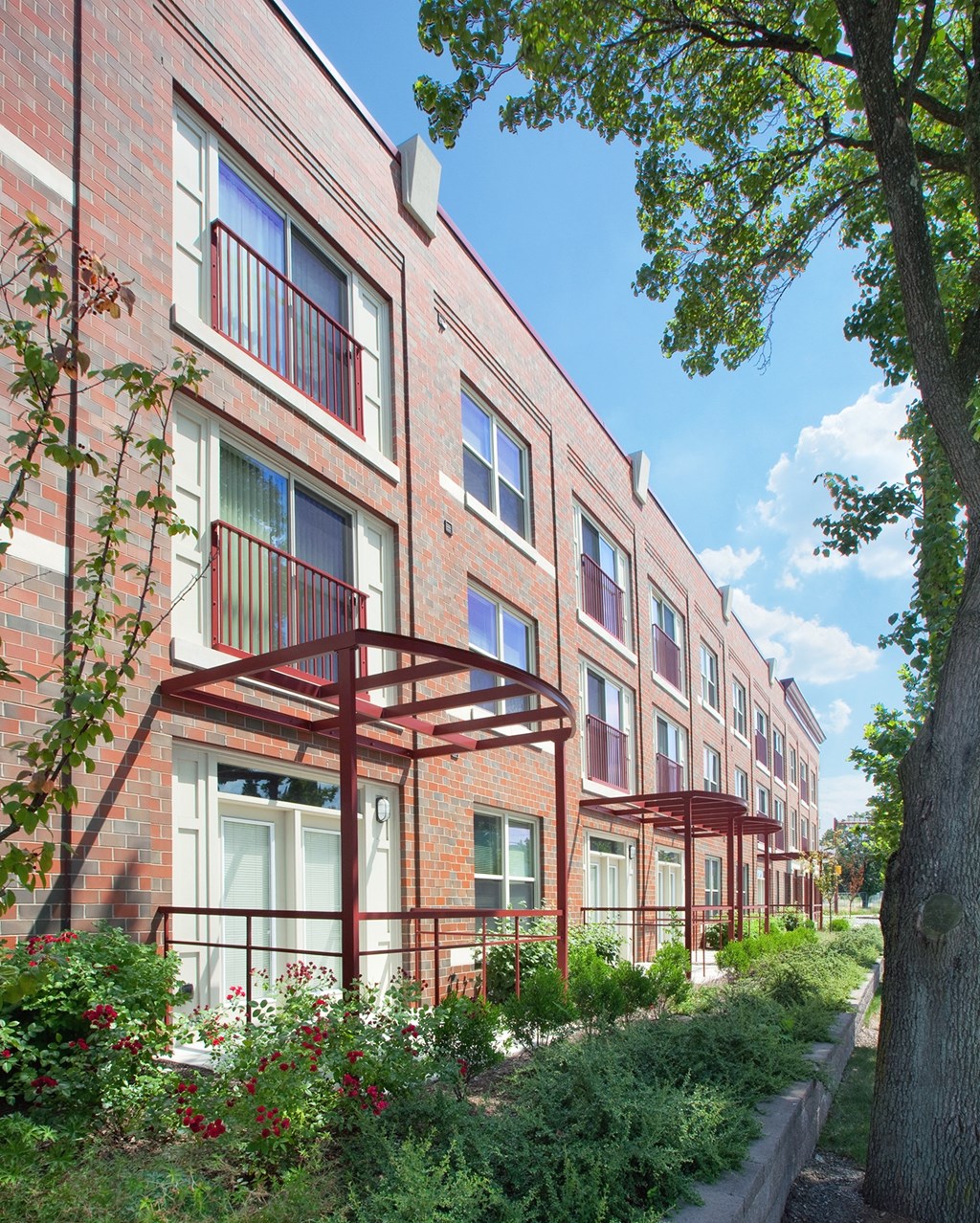 a row of brick apartment buildings with balconies and trees