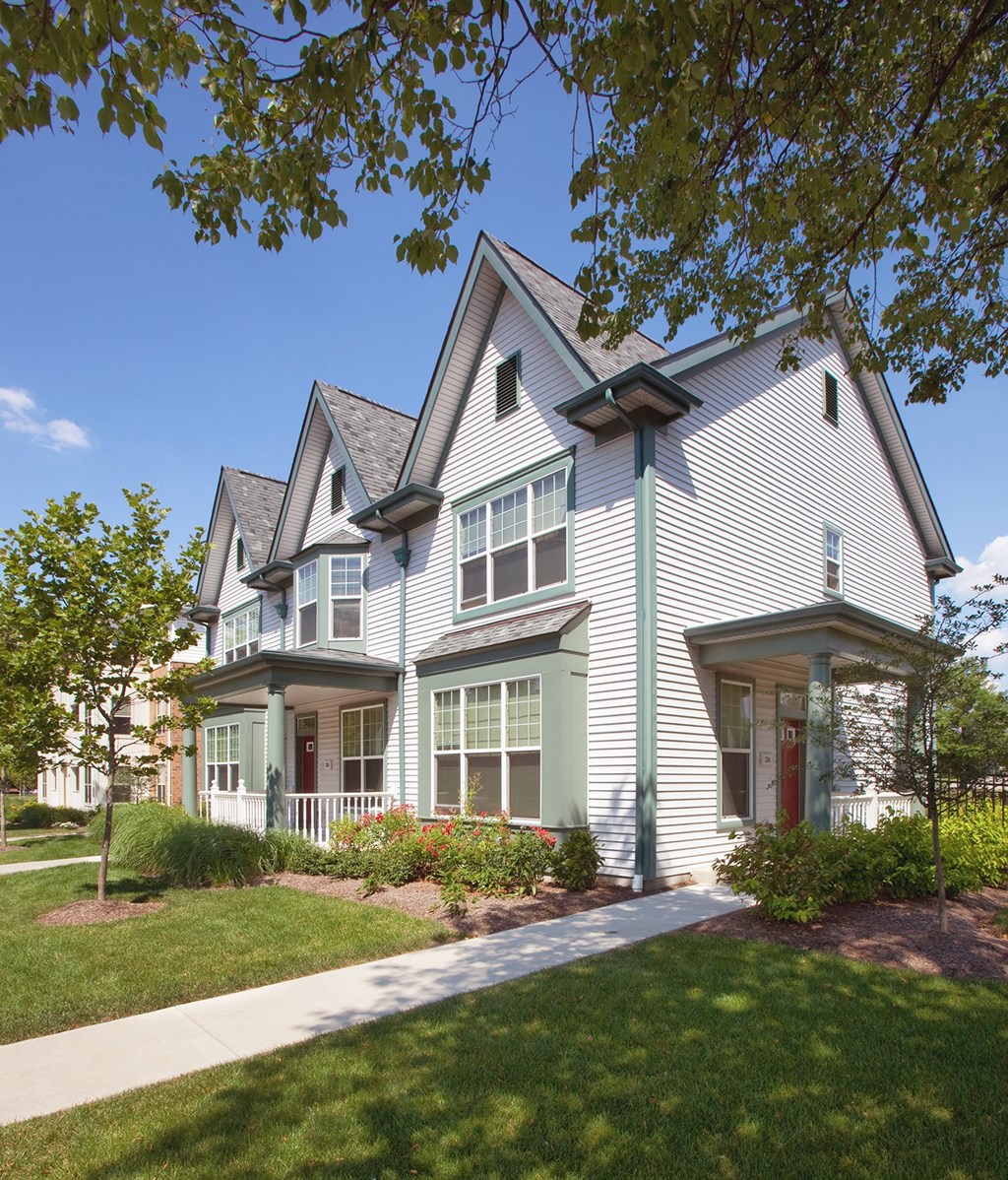 a white house with green trim and a sidewalk