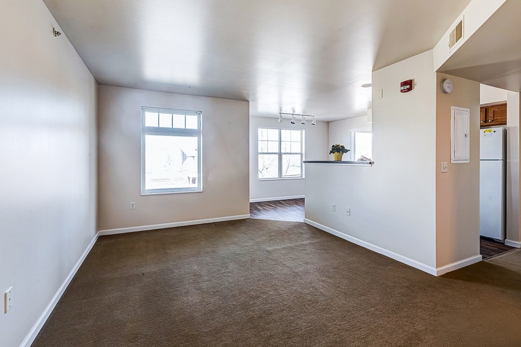 A large empty room with a window and a door leading to another room.