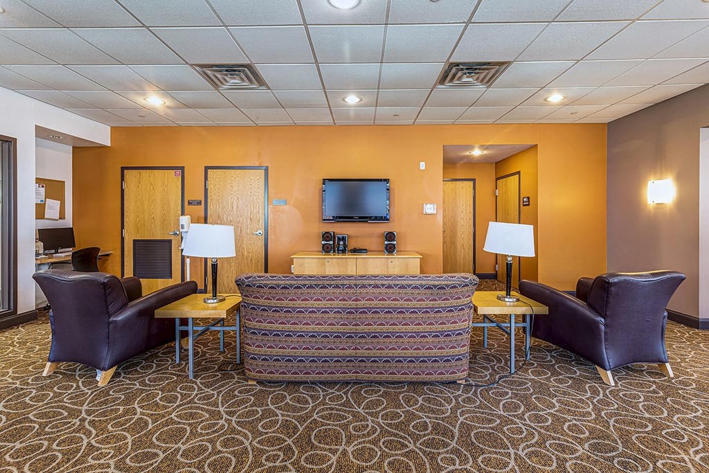 A hotel room with a sofa, chairs, and a television.