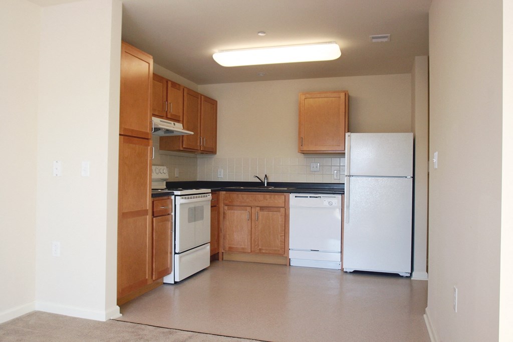 an empty kitchen with white appliances and wooden cabinets