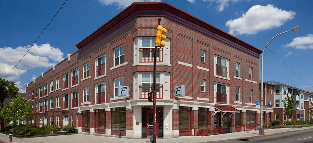 a red brick apartment building on the corner of a street with a traffic light