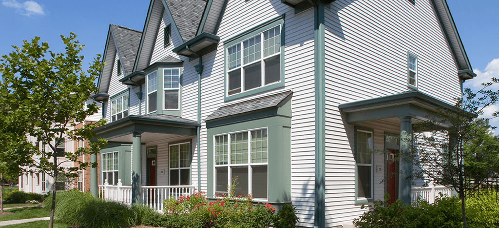 the outside of an apartment home with white siding and green trim