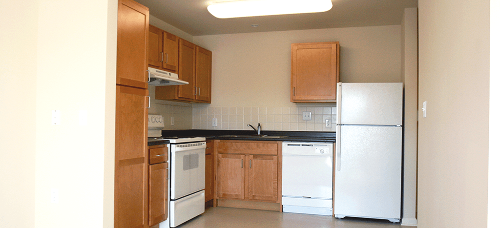an empty kitchen with white appliances and wooden cabinets