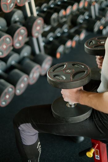 A man is lifting a dumbbell in a gym.