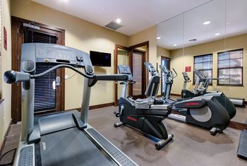 A treadmill and a stationary bike are in a gym.
