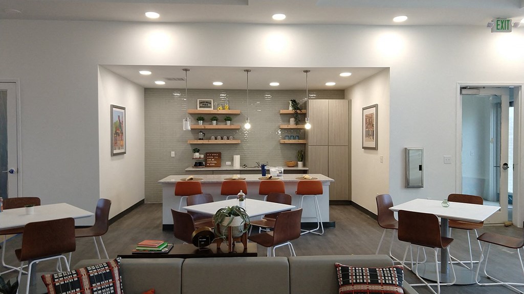 a break room with tables and chairs and a kitchen