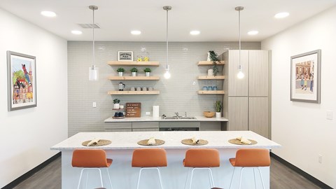 A modern kitchen with a white table and orange chairs.