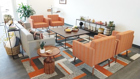 A living room with orange chairs and a grey couch.