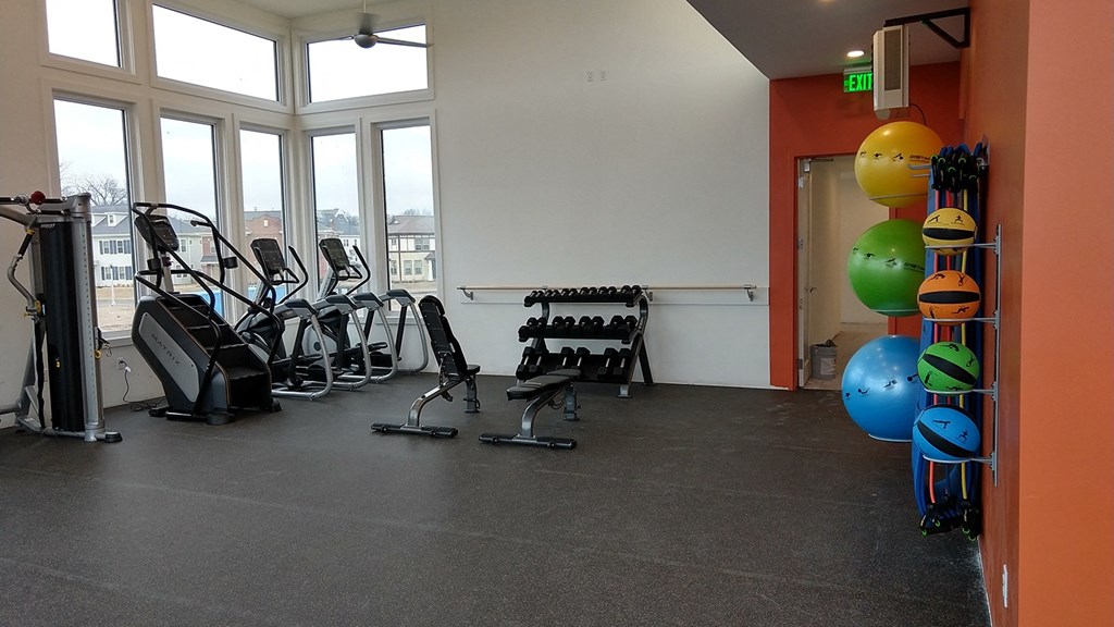 a workout room with cardio equipment and windows in a building