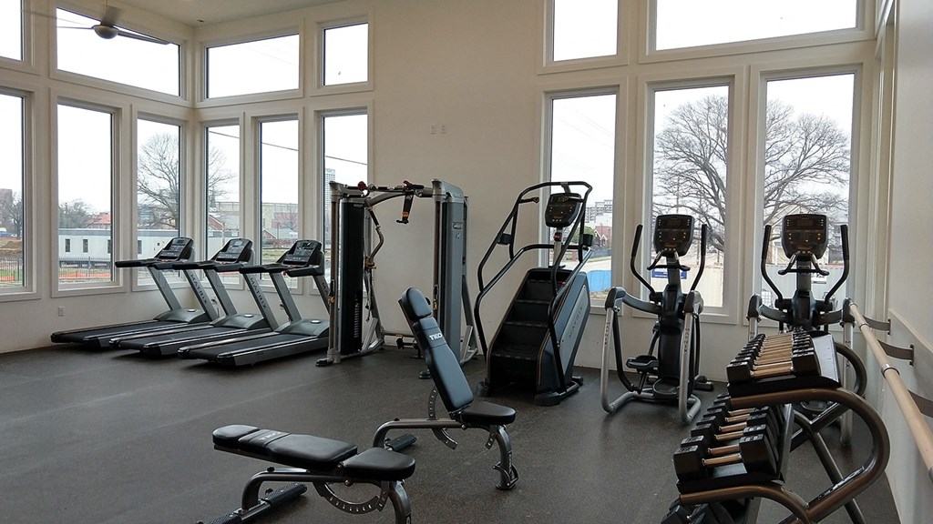 a fitness room with cardio equipment and large windows