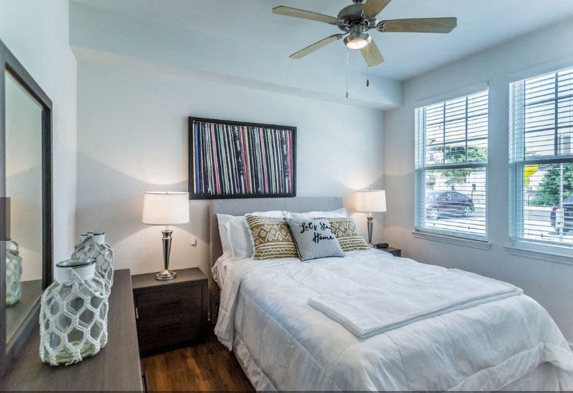 a bedroom with a white bed and a ceiling fan